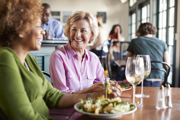 Group of adults talking at a restaurant table with background noise