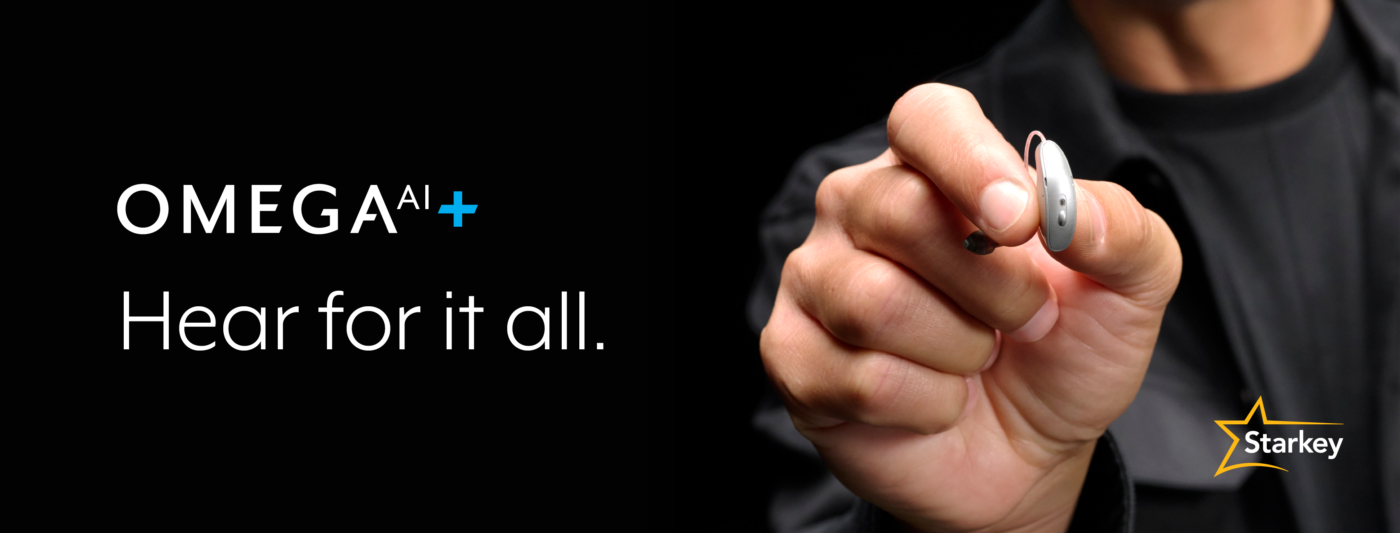 Hand holding a small Omega AI+ hearing aid beside the message “Hear for it all”